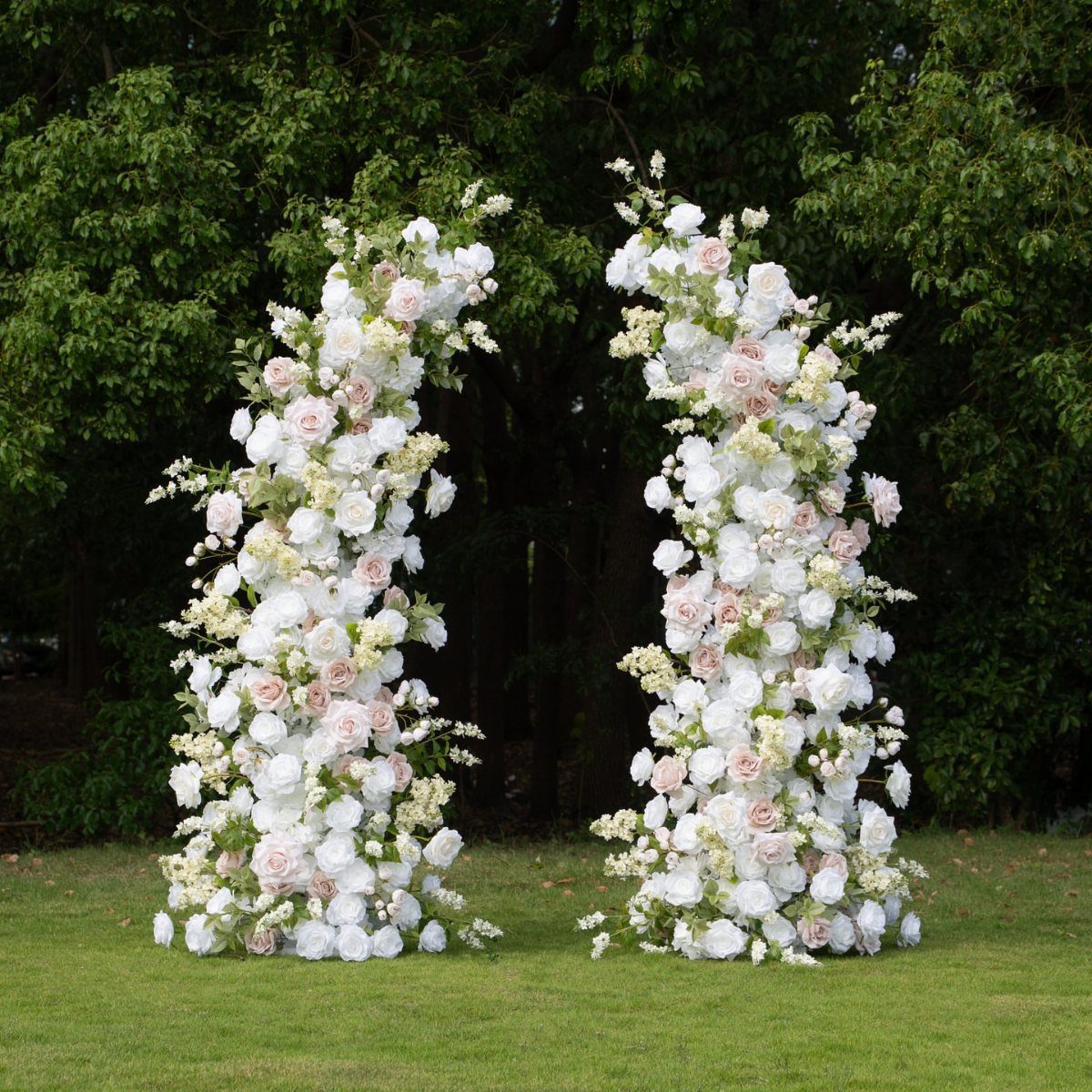 Broken wedding arch with white and pink roses on a green lawn