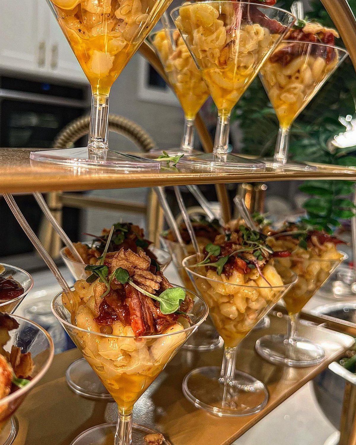 Macaroni and cheese appetizers with bacon in martini glasses on a gold stand.