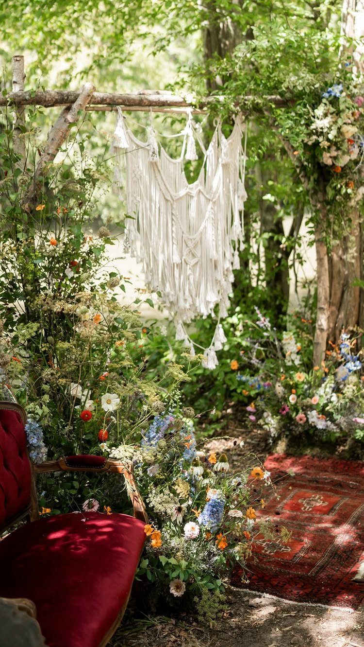 Macrame backdrop and colorful wildflowers decorating a rustic outdoor wedding ceremony space.