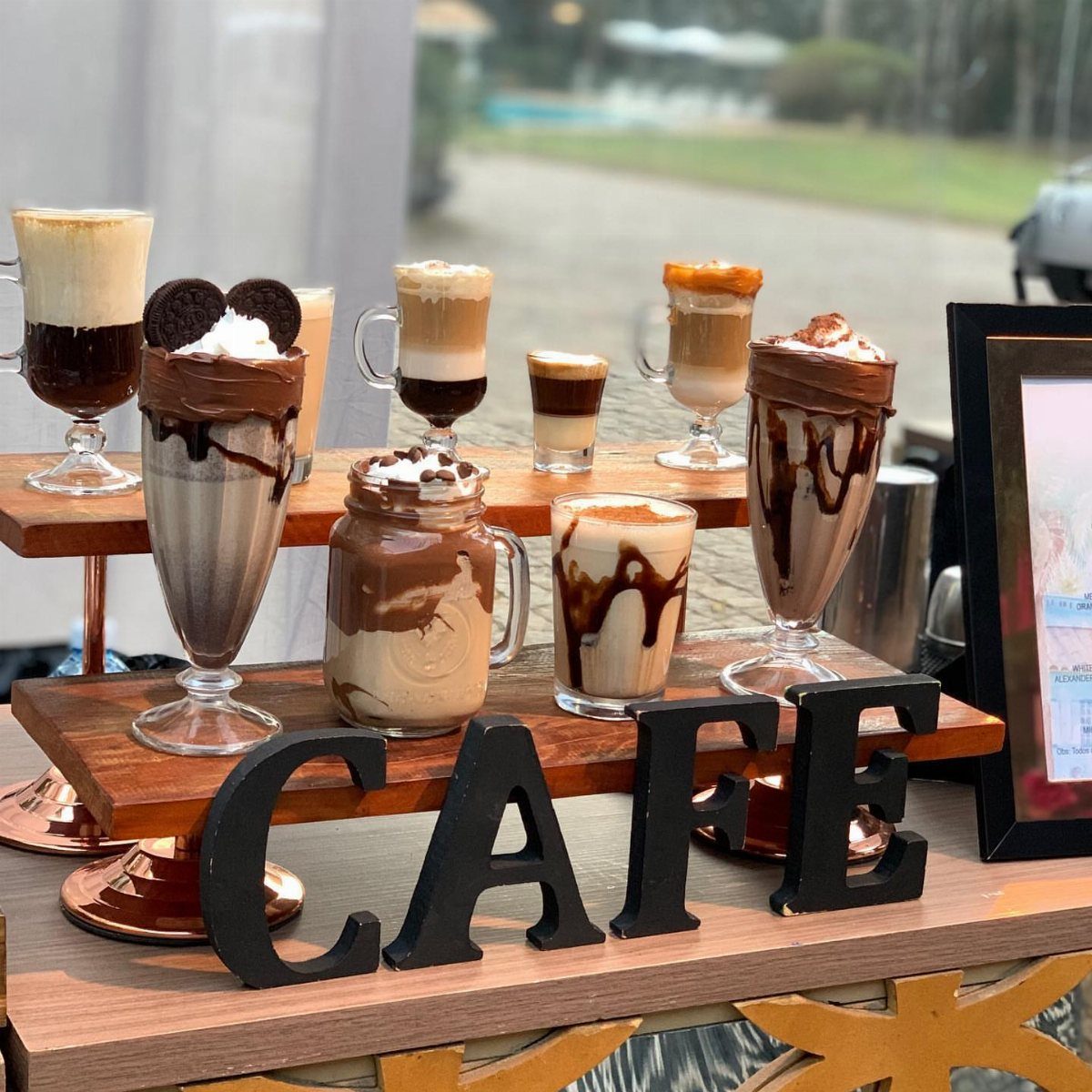 Assorted coffee and chocolate drinks on wooden shelves with a black CAFE sign.