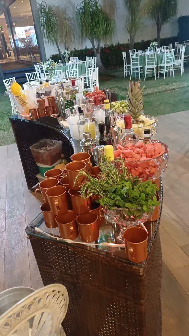 Outdoor cocktail station with copper mugs, fresh fruit, herbs, and liquor bottles.