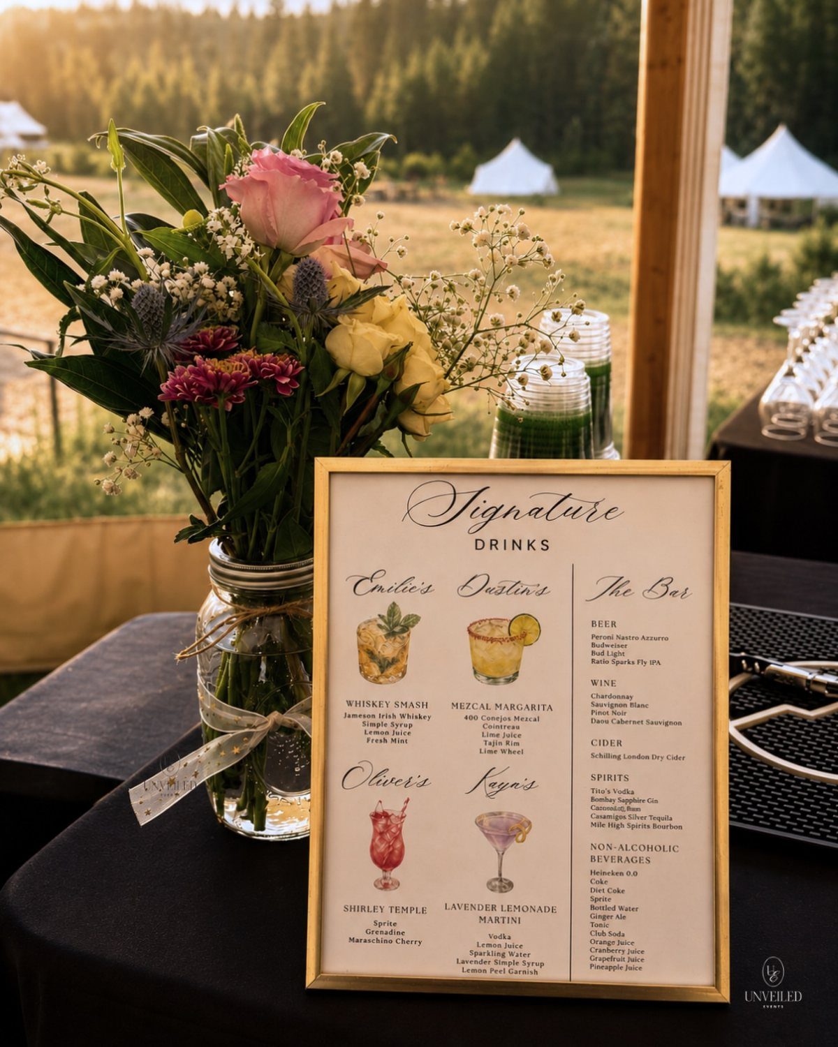 Signature drinks menu in gold frame next to flowers on a wedding bar.