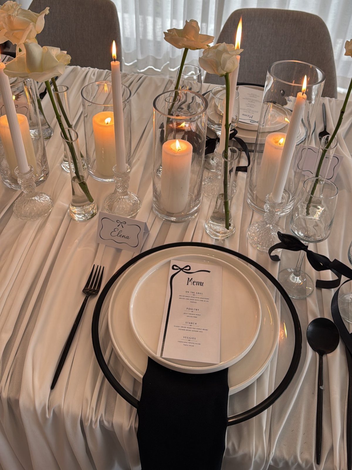 Wedding table setting with white flowers and lit white candles on white linens