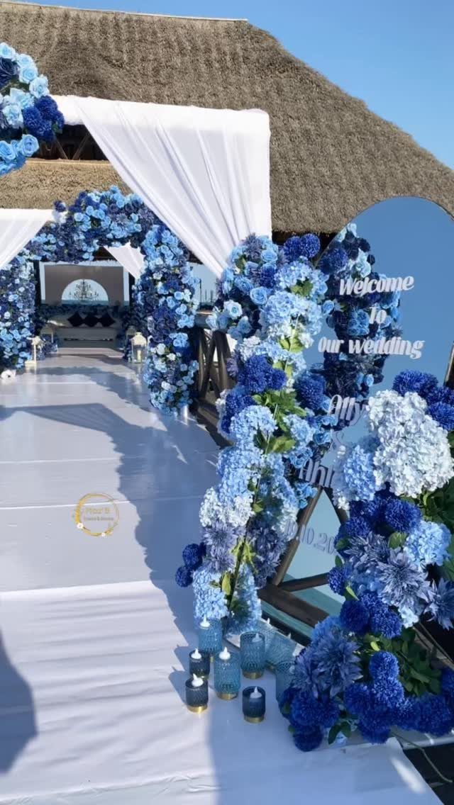 Wedding aisle decorated with blue hydrangea floral arches and a white fabric canopy.