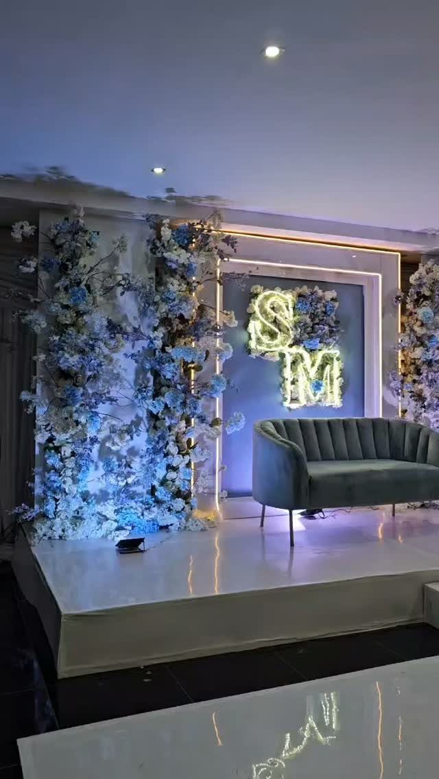 Blue velvet sofa on a white platform surrounded by dusty blue and white blossoms