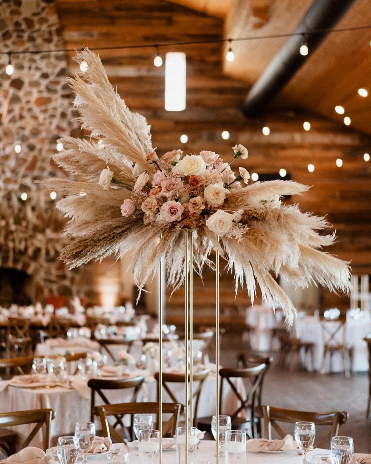 Tall gold stand with pampas grass and roses as a wedding centerpiece.