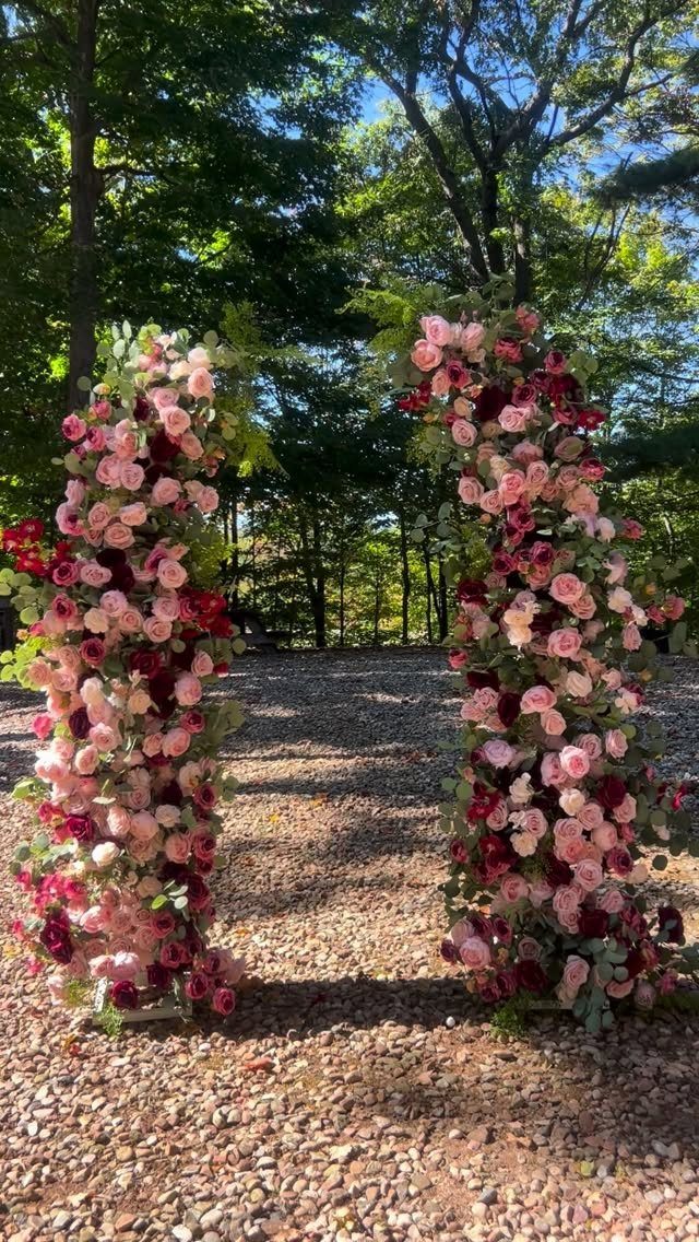 Floral wedding arch with burgundy and pink roses in a wooded outdoor setting
