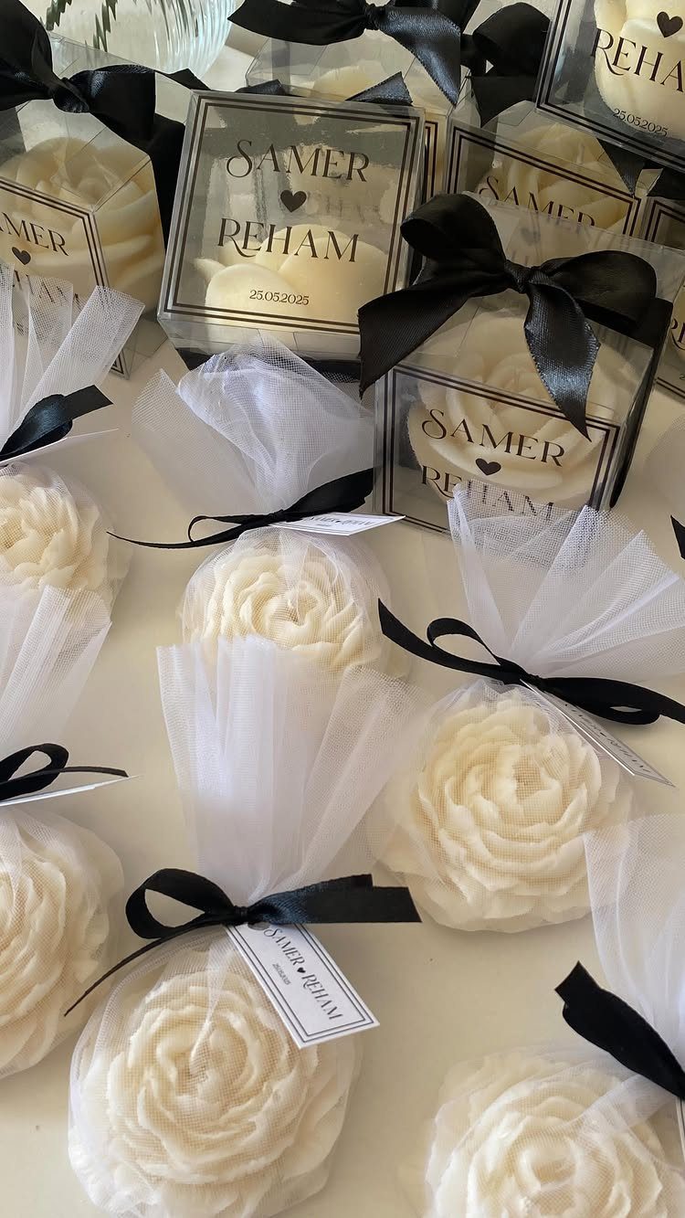 Rose-shaped white candles in clear boxes and tulle wraps with black ribbons.