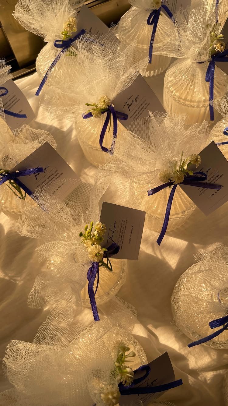 Small white candles wrapped in tulle with blue ribbons and name cards.
