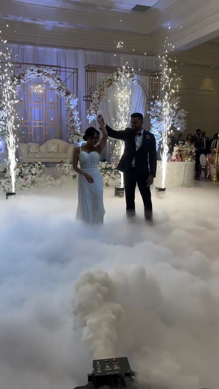 Bride and groom dancing on a fog-covered floor with cold spark fountains.