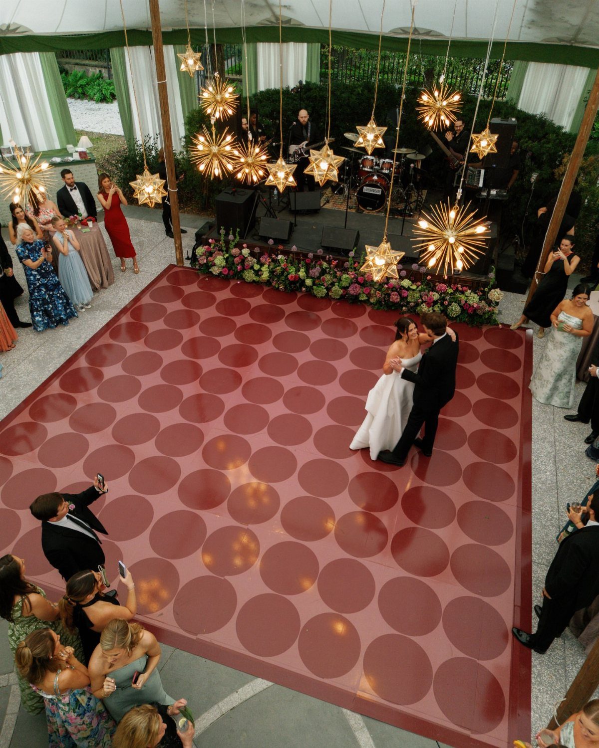 Couple dancing on a red patterned dance floor under star-shaped hanging lights.