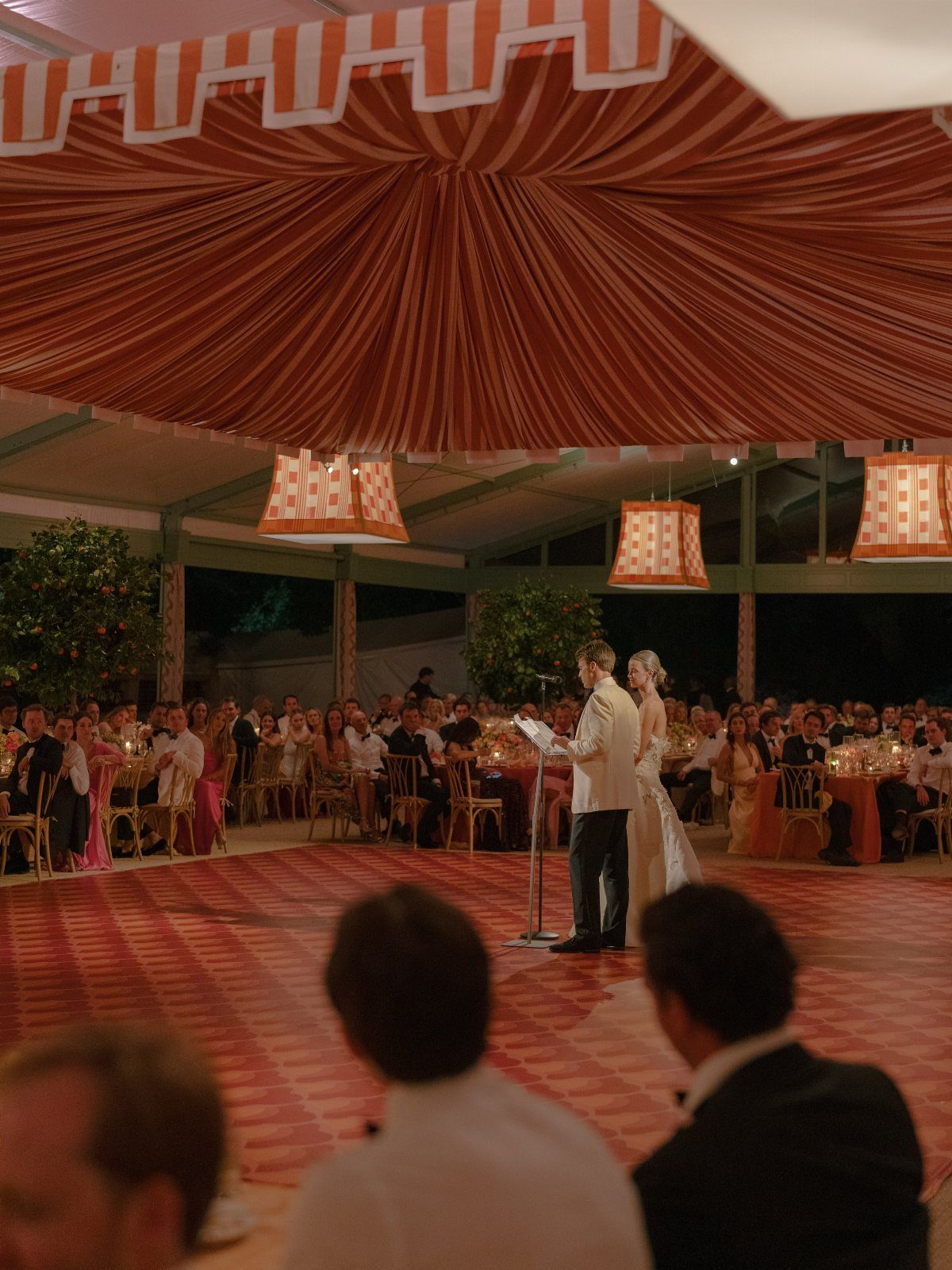 Couple standing on a circular red patterned dance floor at a wedding reception