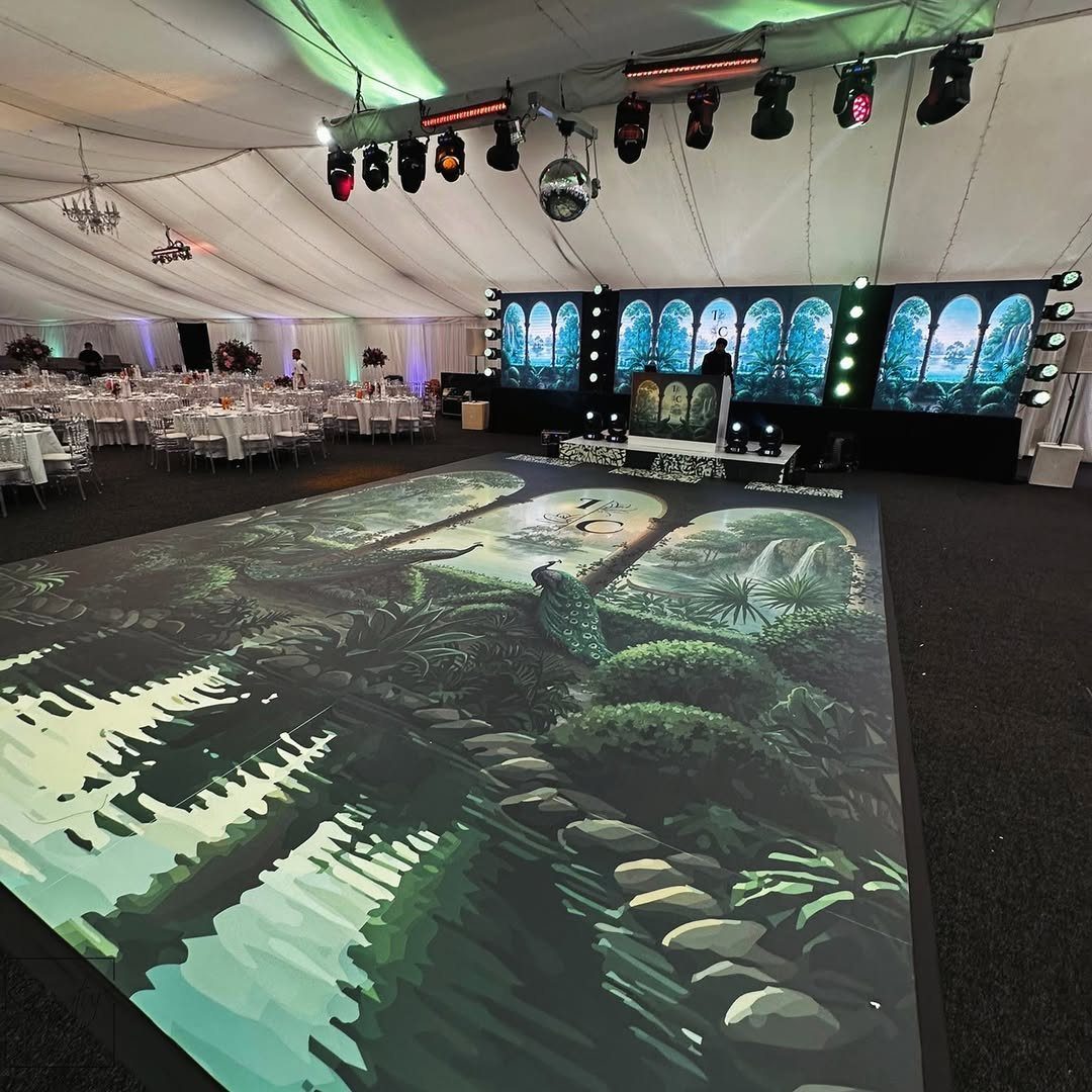 Jungle landscape printed dance floor inside a white wedding tent with event lighting.