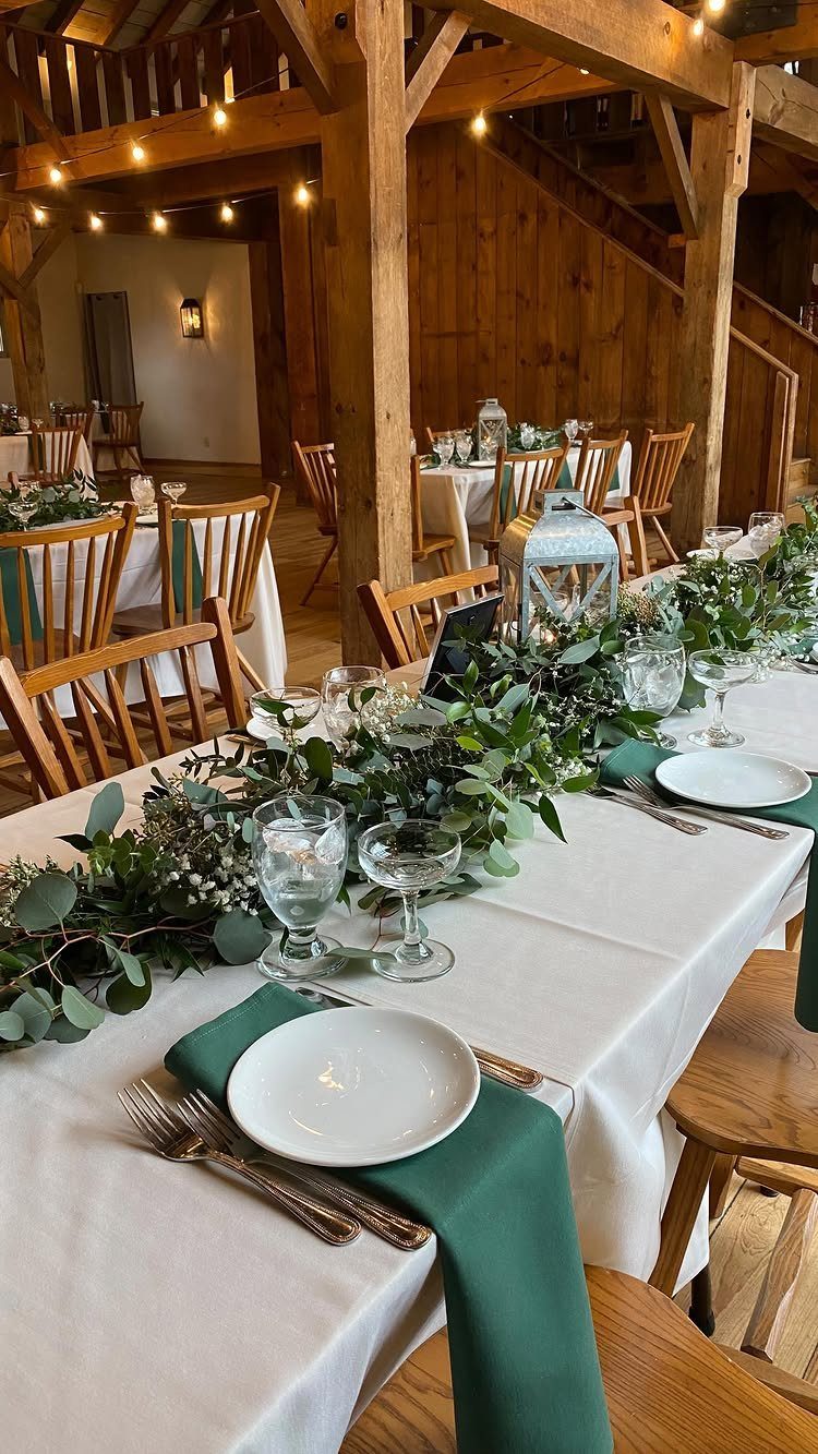 Eucalyptus greenery runner on a white wedding table in a rustic wooden barn.