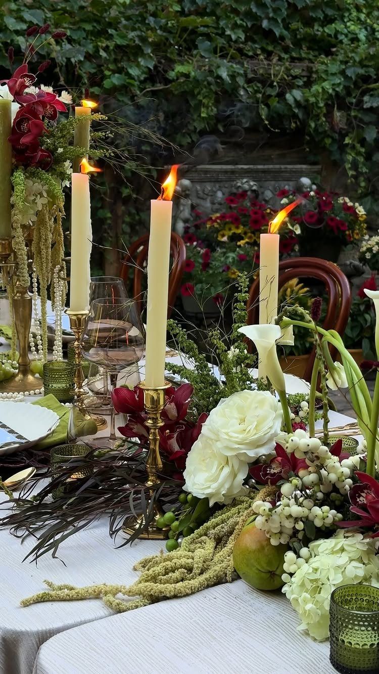 Floral arrangements with burgundy orchids and emerald greenery on a wedding table.
