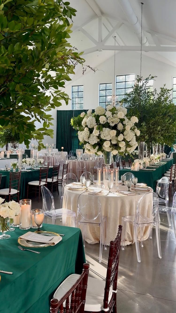 Wedding reception tables with emerald green and champagne linens and white floral centerpieces.