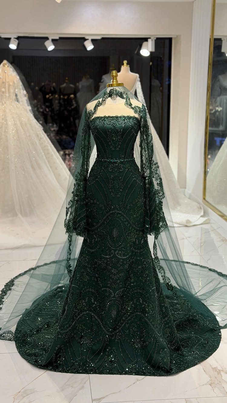 Emerald green sequined mermaid wedding dress with a sheer cape on a mannequin
