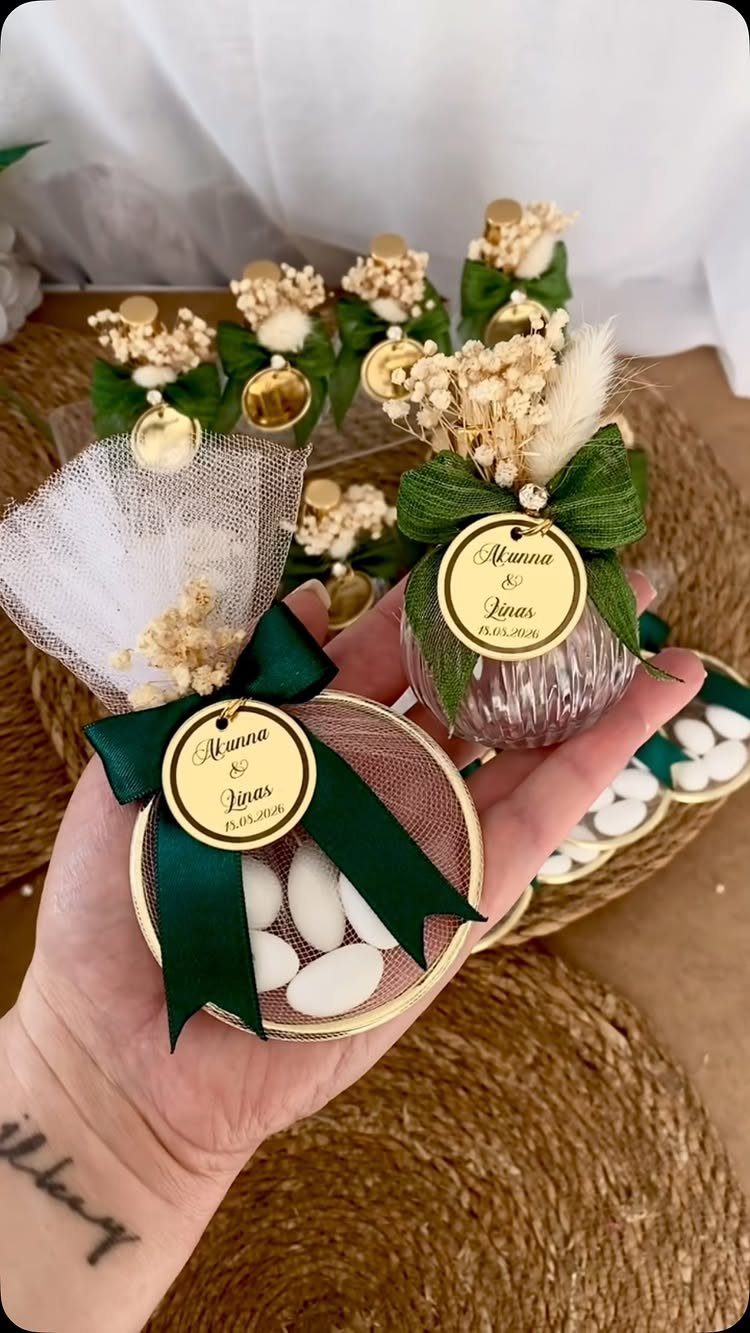 Wedding favors with emerald green ribbons, gold tags, and dried white flowers.
