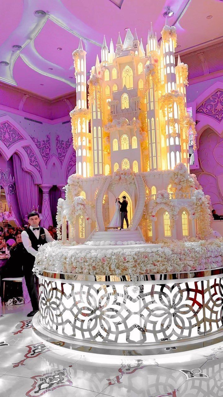 Massive golden castle wedding cake with a bride and groom in the center.