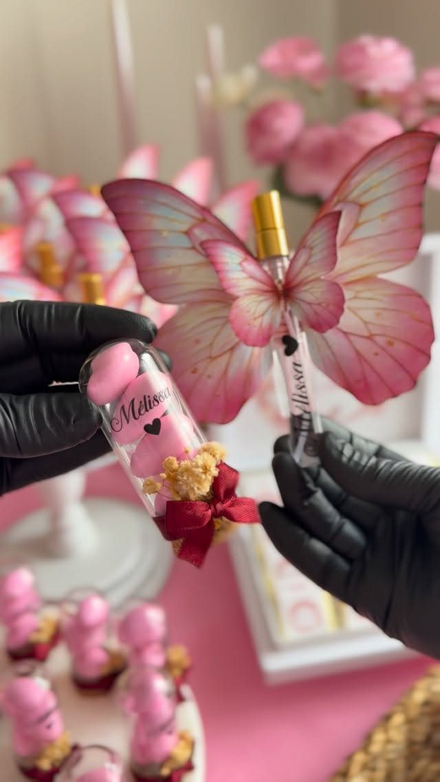 Small glass vials with a teddy bear and butterfly wings as wedding favors.