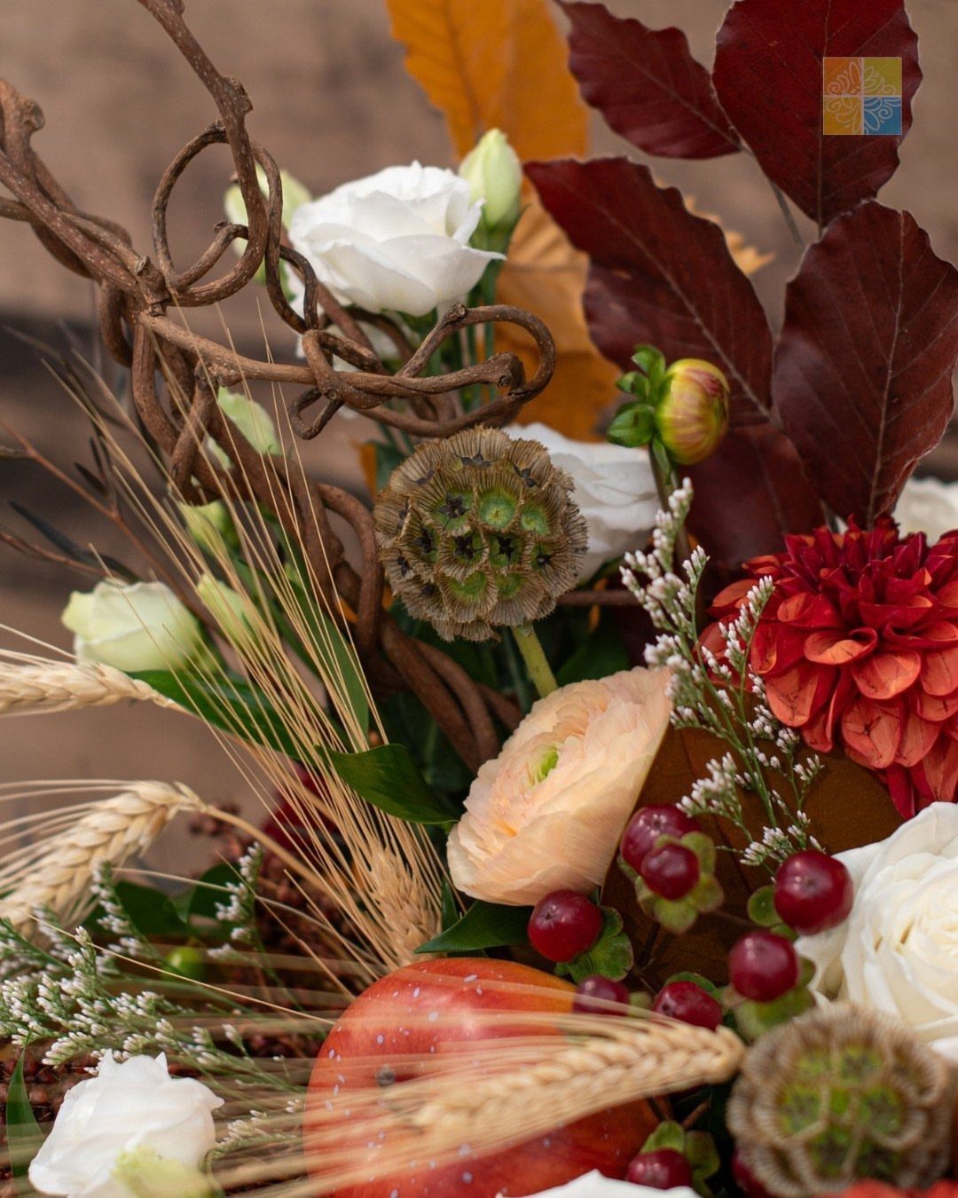Autumn floral arrangement with white roses, red dahlia, wheat, and dark burgundy leaves.