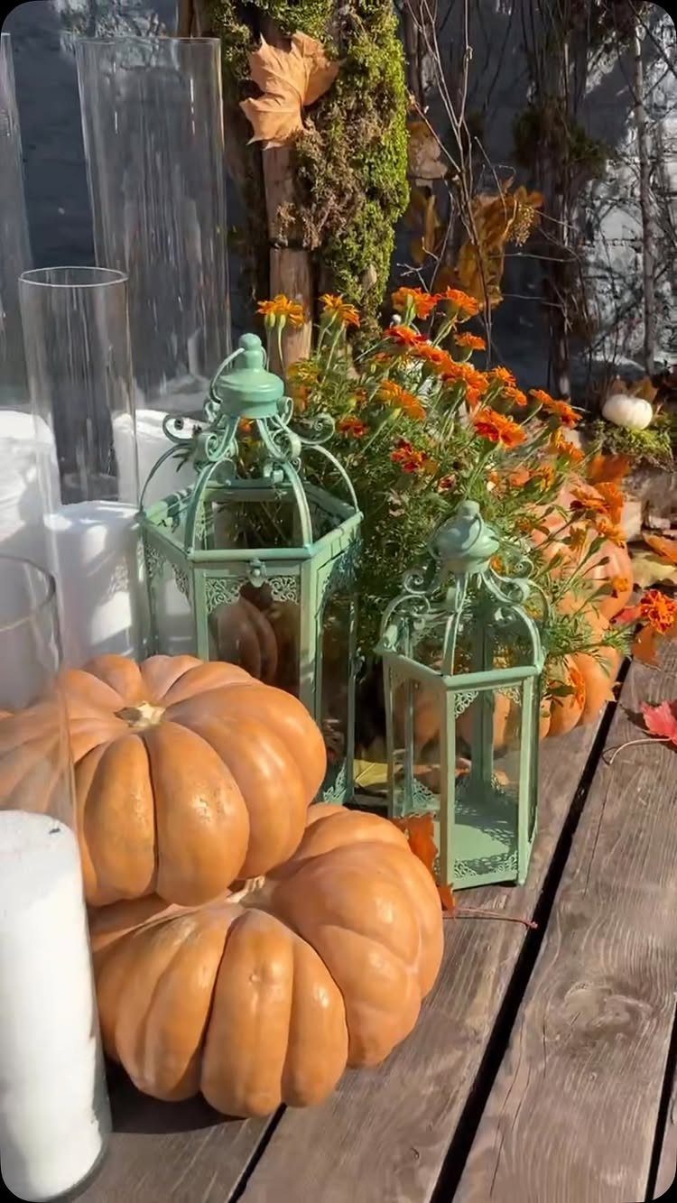 Orange pumpkins and mint green lanterns with autumn flowers on a wooden table