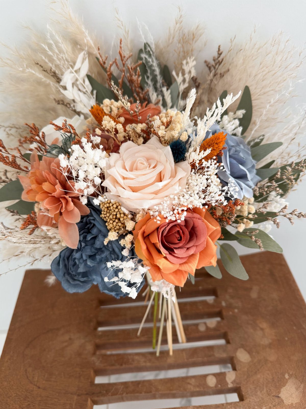Bridal bouquet with burnt orange and dusty blue roses and dried pampas grass.