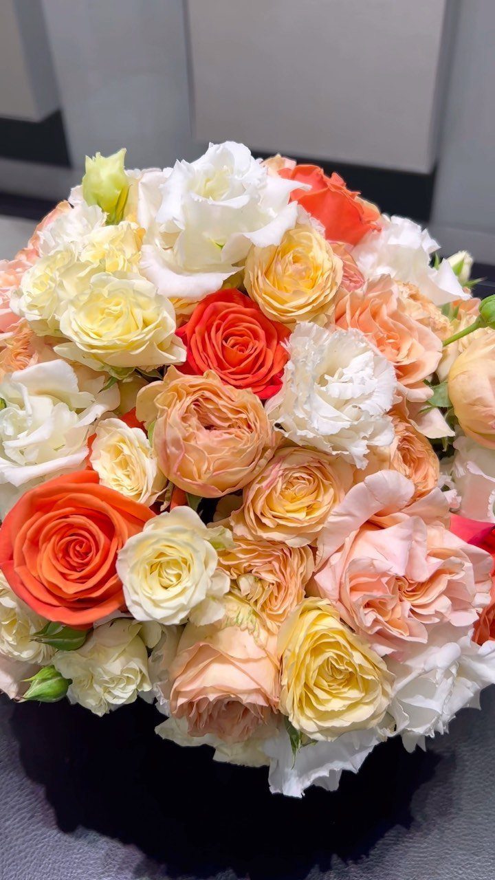 Bridal bouquet with peach, orange, and white roses and lisianthus flowers.