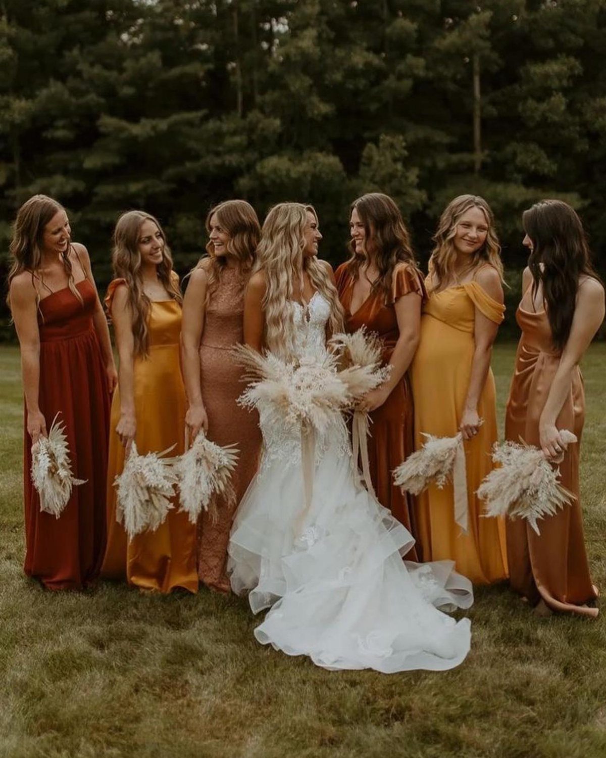 Bride in white gown with bridesmaids in burnt orange and mustard yellow dresses.