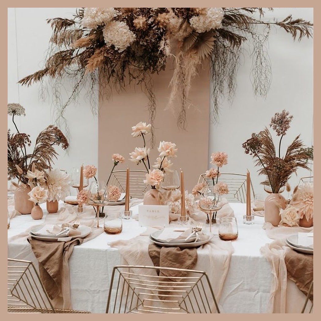 Champagne wedding table setting with neutral floral arrangements and gold wire chairs.