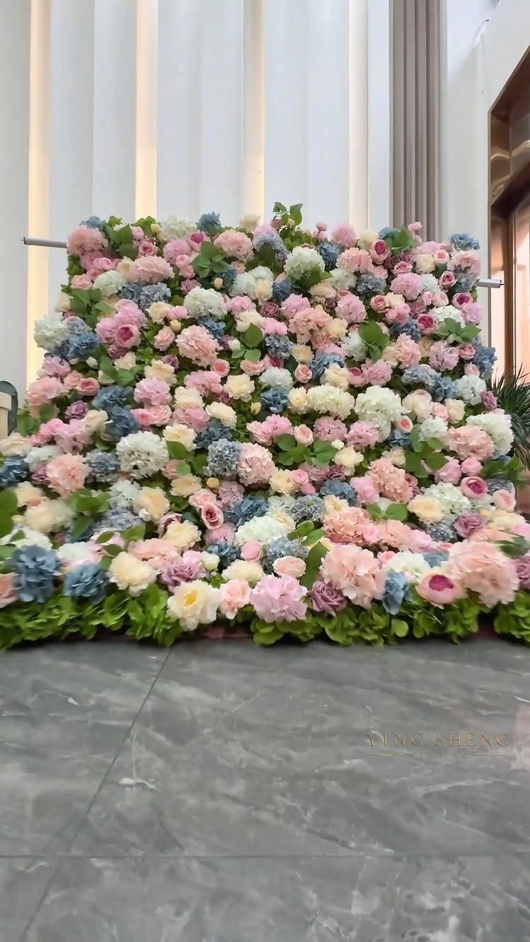 Flower wall with pink, white, and blue blooms against a white background.