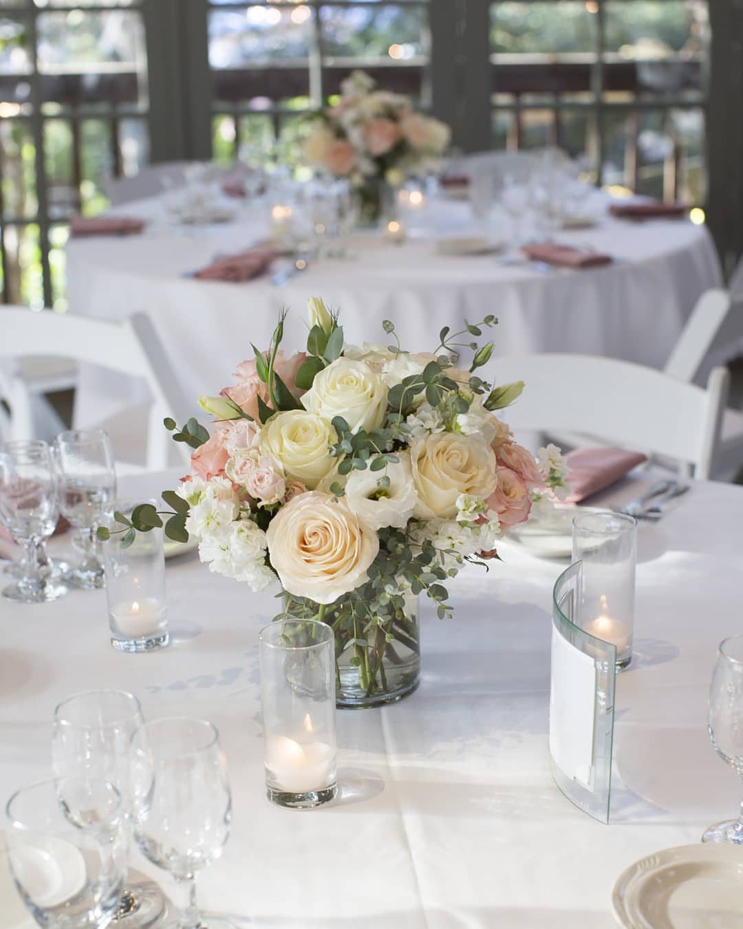 White and peach rose centerpiece on a wedding reception table with candles