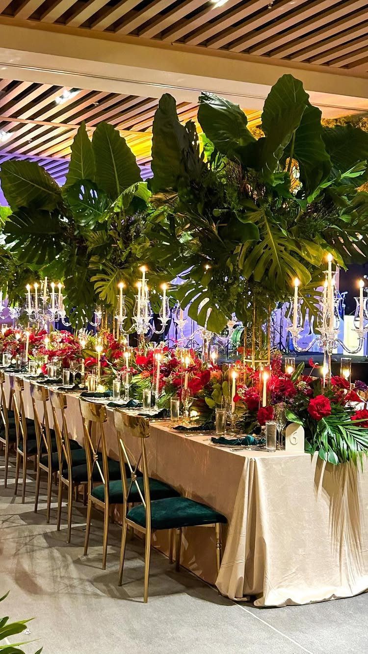Tall tropical leaf centerpieces and red flowers on a wedding reception banquet table