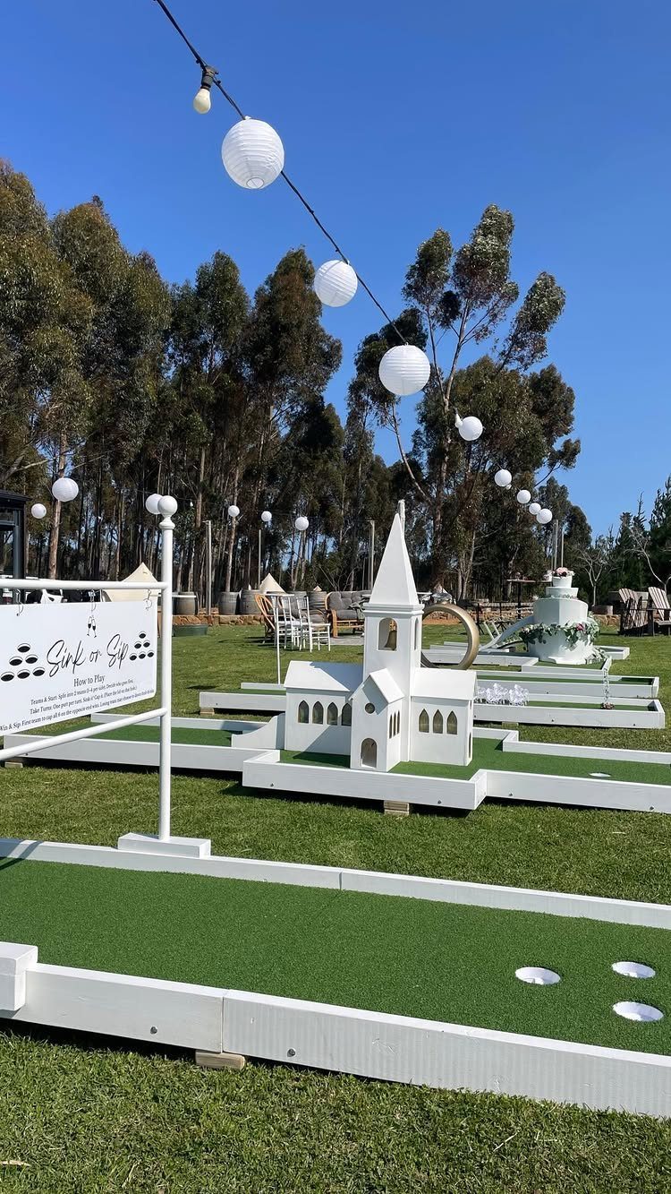 Miniature golf course with a white model church on a green lawn.