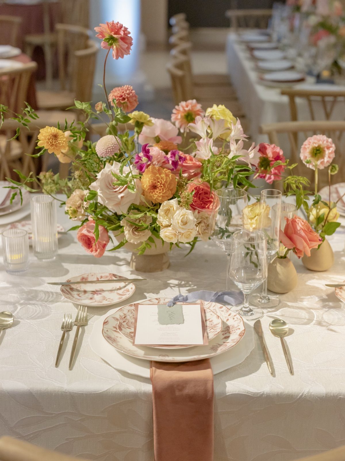 Floral centerpiece with pink and yellow blooms on a set wedding table.
