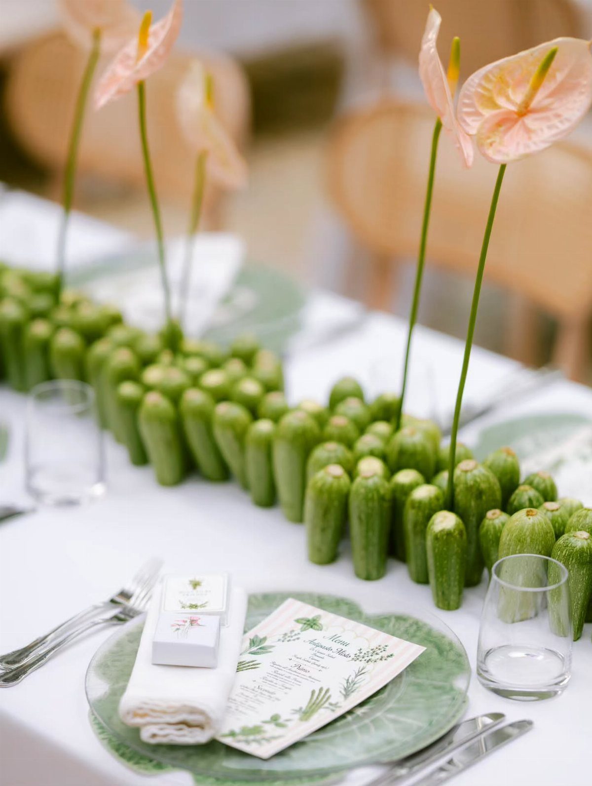 Cucumber centerpiece with pink anthurium flowers on a white wedding table setting