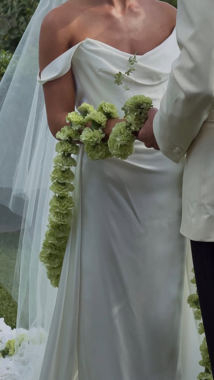 Bride in white gown holding a cascading bouquet of light green flowers