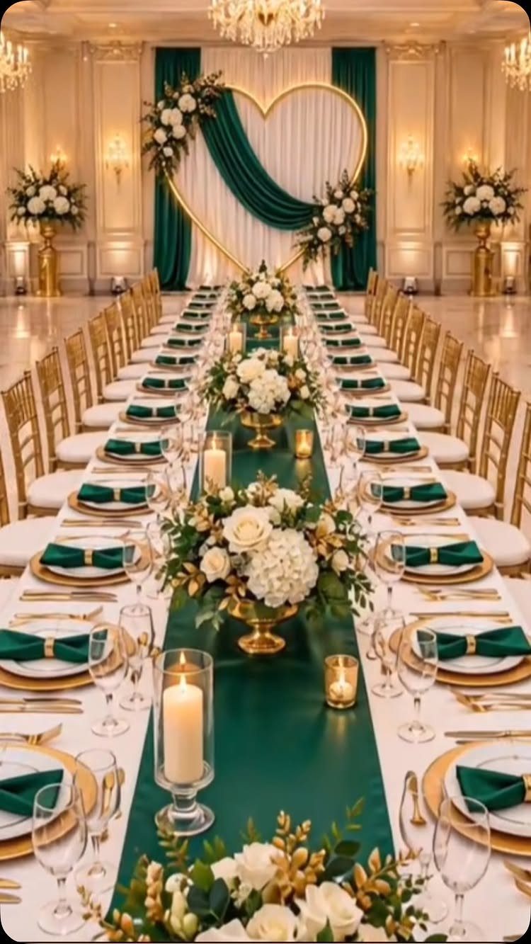 Emerald green and gold wedding table setting with white floral centerpieces and heart arch.