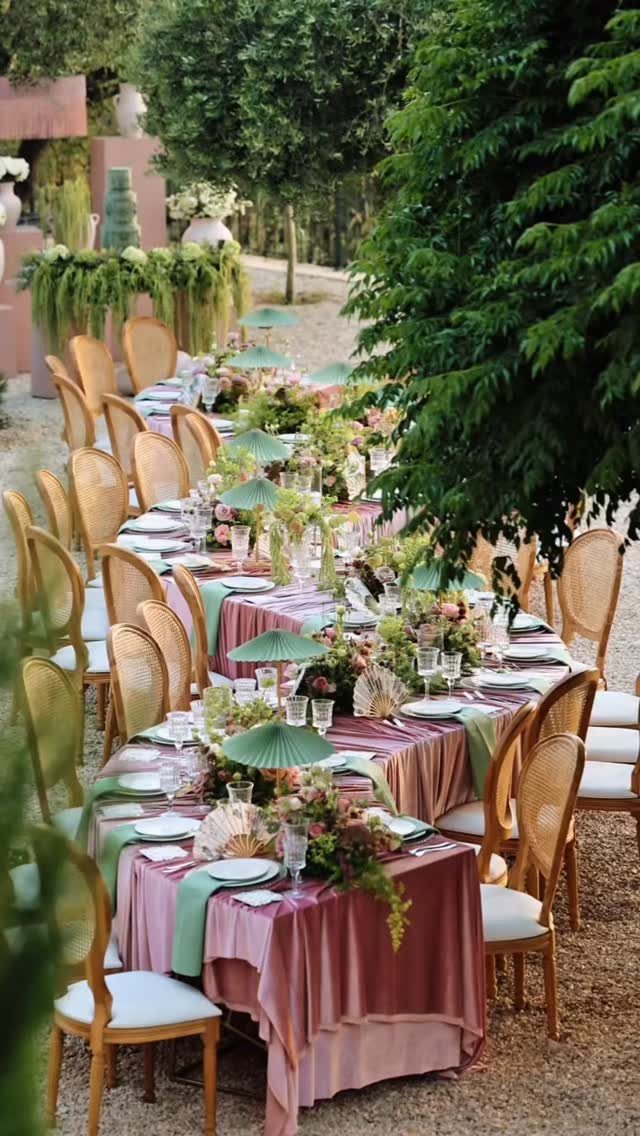 Outdoor wedding table with dusty rose linens, sage green runners, and pink floral centerpieces.