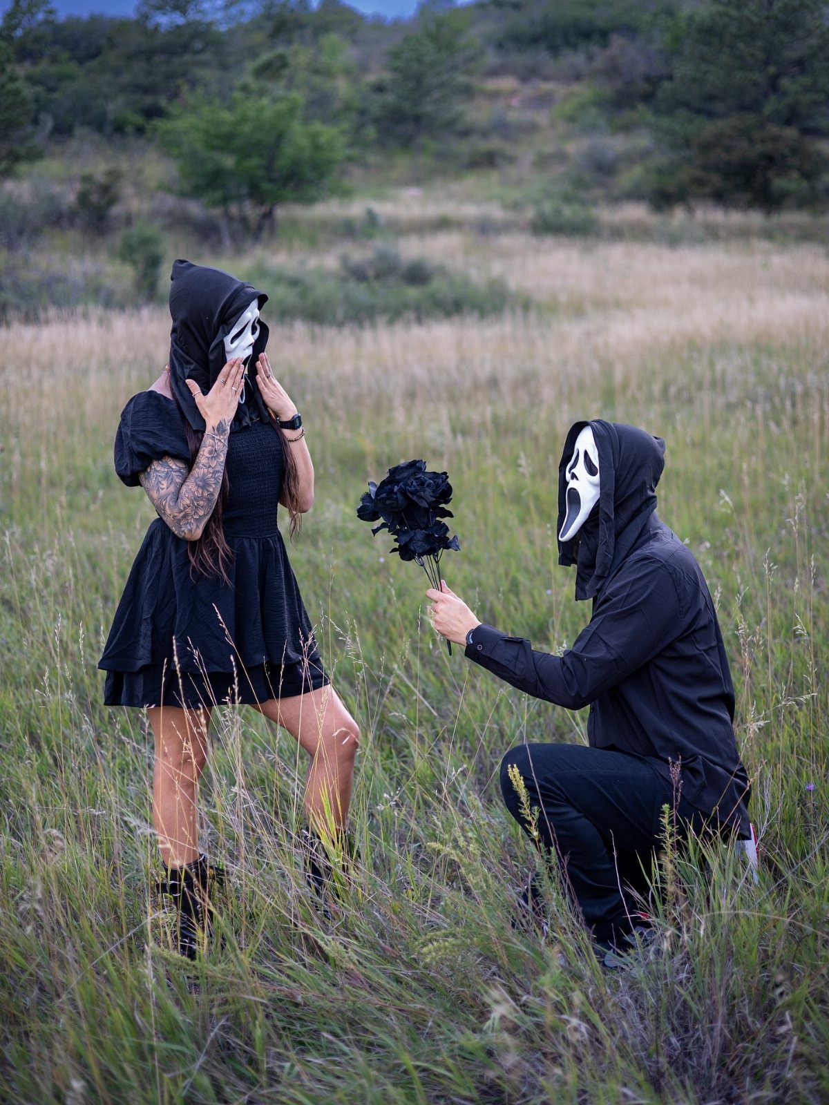 Couple in Ghostface masks and black clothing posing for a spooky engagement photo.