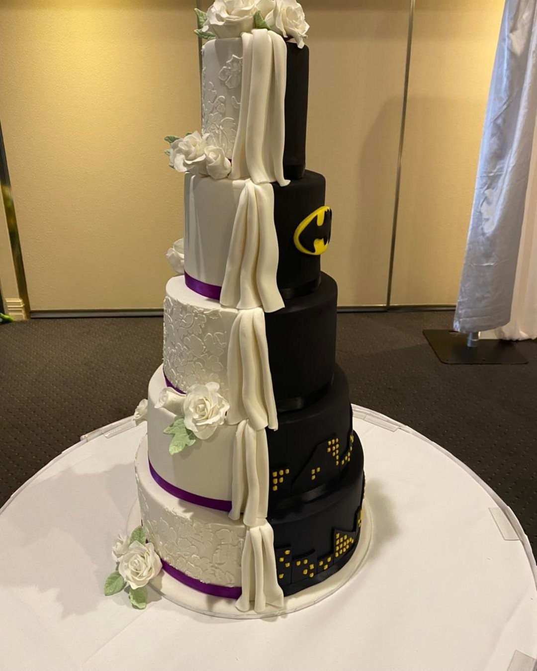 Split wedding cake with white lace and black Batman themed decorations