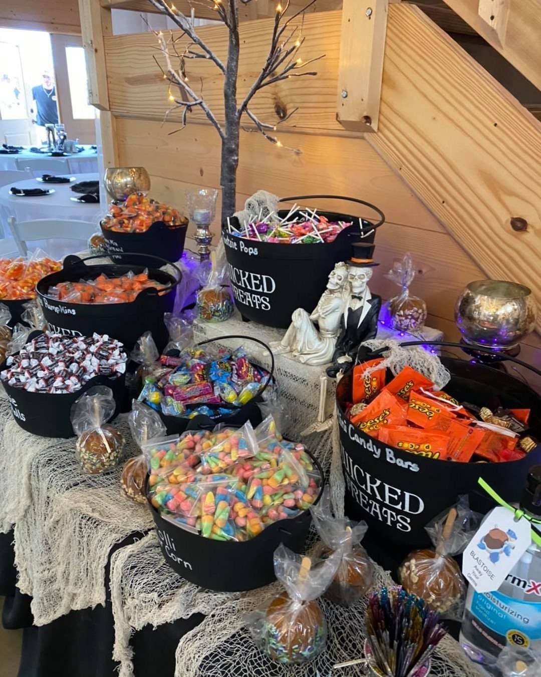 Candy buffet with black buckets of sweets and spooky decor for a wedding.