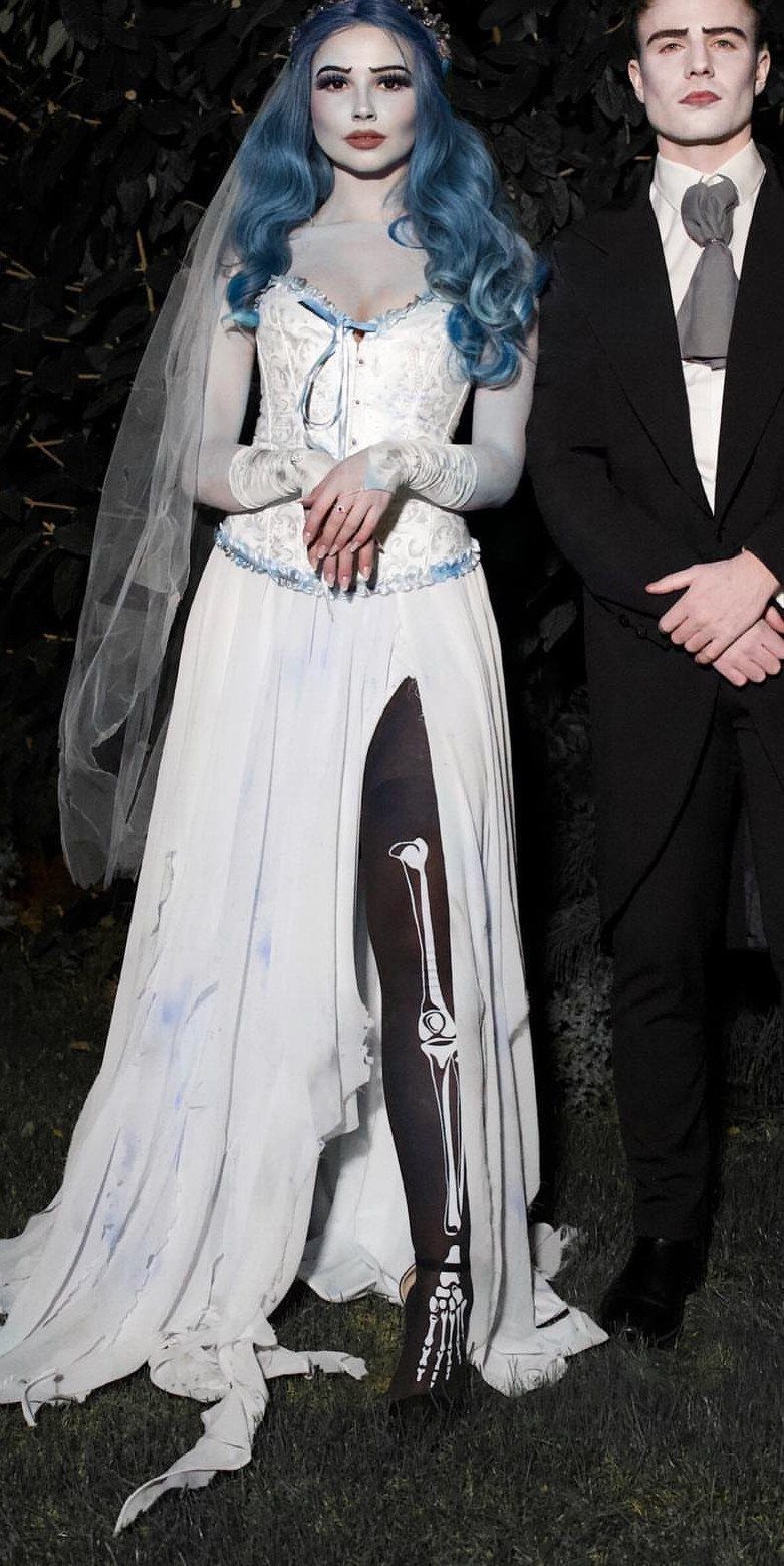 Couple in spooky wedding attire featuring a tattered bridal gown and black suit.