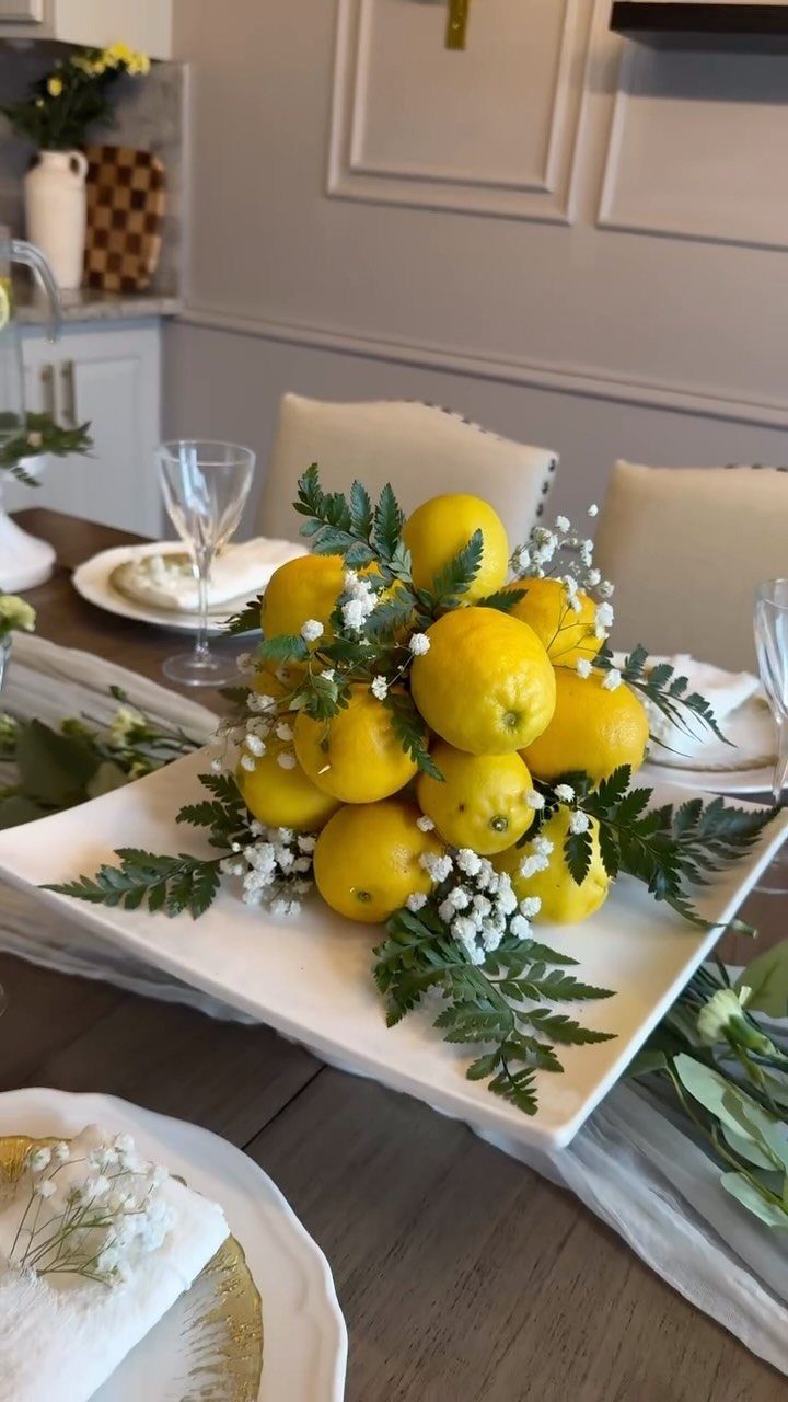 Yellow lemon centerpiece with baby's breath and ferns on a white square plate.