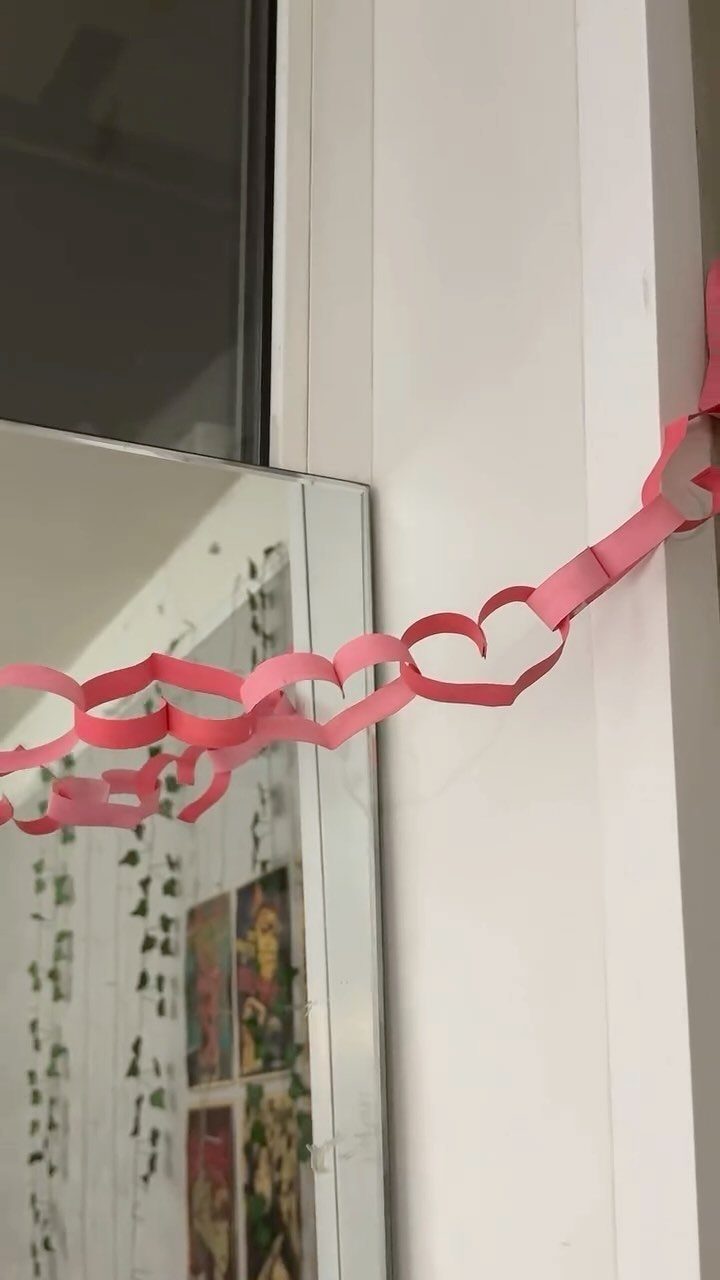 Pink paper heart chain draped across a white door frame and mirror.