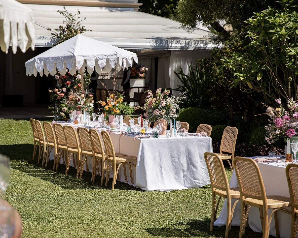Outdoor wedding table with peach runner and pastel floral arrangements on green grass