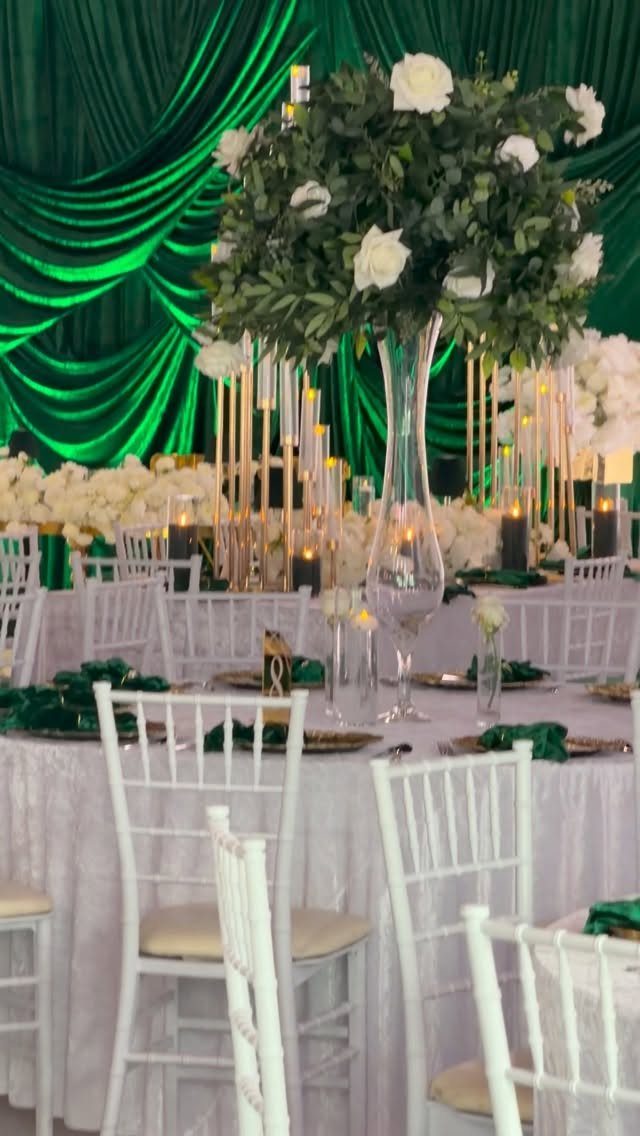 Wedding table with white roses and emerald green draped fabric background.