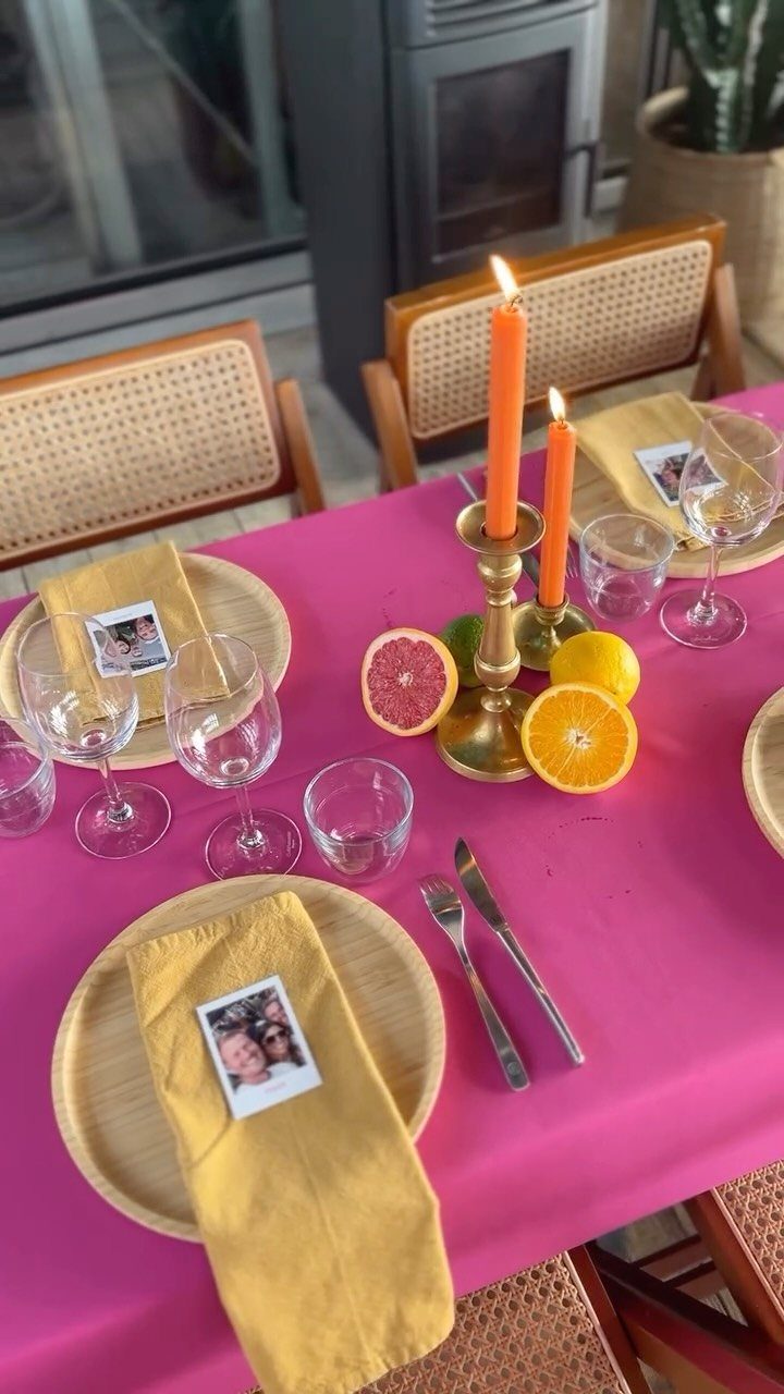Fuchsia tablecloth with yellow napkins, orange candles, and citrus fruit for a vibrant setting.