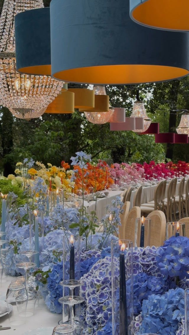 Vibrant blue, yellow, and fuchsia floral table arrangements under colorful oversized lampshades.