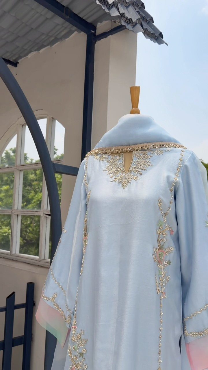 Light blue embroidered traditional dress on a mannequin torso outdoors.